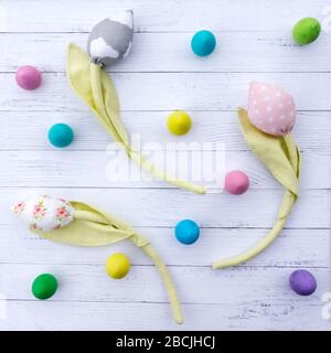 Wooden easter eggs and fabric tulip flowers on a white background from aged boards. Abstract easter background for greeting banner or sale post on Ins Stock Photo