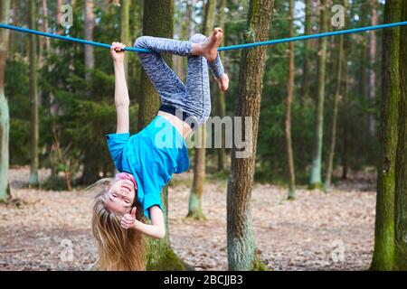 Young child girl hanging on rope upside down on playground in park Stock Photo