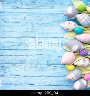 Beautiful textile tulips and multi-colored wooden Easter eggs on a background of aged blue boards. Easter mockup in a rustic style. Easter background Stock Photo