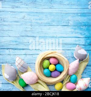 Rustic easter background for advertising or banner, Instagram post. Patchwork tulips from textile and multi-colored Easter eggs on a background of blu Stock Photo