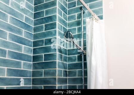 Modern minimalistic bathroom with blue green tiles tiled shower and head in bright room with curtain Stock Photo