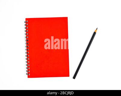 Black pencil beside a red color covered single note paper diary isolated on an empty white background Stock Photo
