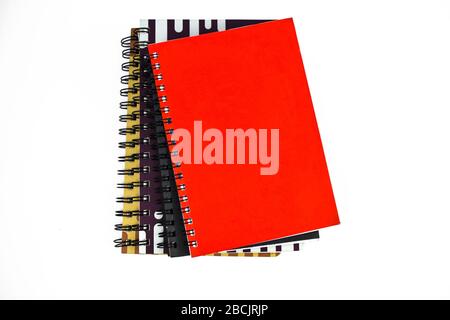 Four different color covered paper note books gathered on top of each other on a white background Stock Photo