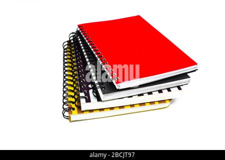 Side view of four different color covered paper note books gathered on top of each other before a white background Stock Photo