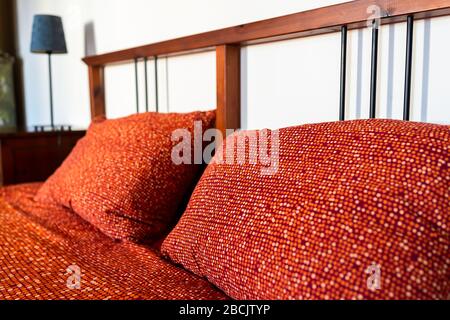 Antique vintage retro bedroom with red orange pattern bed pillow in room with wooden headboard in home in Europe Stock Photo