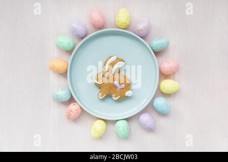 Eggs decoration and gingerbread easter bunny cookie on a plate on pink background. Easter concept. Top view, flat lay, copy space Stock Photo