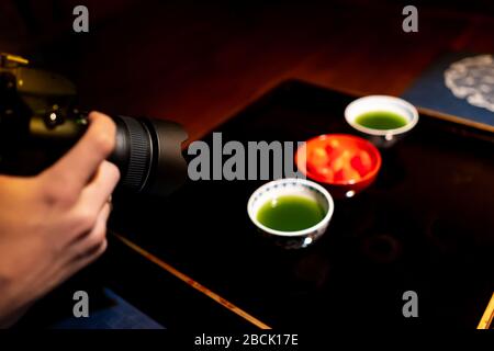 Photographing traditional japanese cups with matcha green tea bowls and strawberries in house with black lacquered wood table and dessert dish backgro Stock Photo