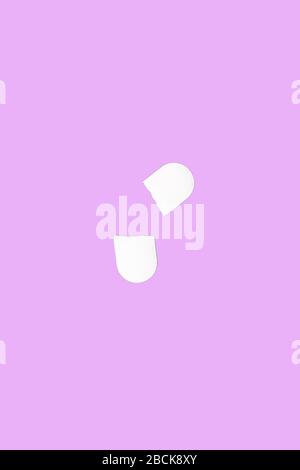 Two halves of a medical pill broken by a dividing notch. Medical pill isolated on a pink background. Flat lay. Copy space. Medical pill concept. Stock Photo