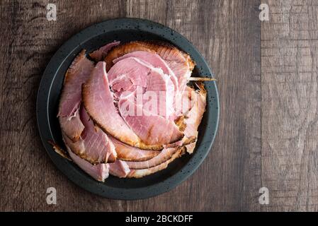 Black plate stacked with sliced ham on a wood table Stock Photo
