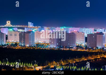 Ashgabat, Turkmenistan skyline at night. Wedding Palace and Ashgabat Hotel visible. Multiple modern white marble buildings with colorful illumination. Stock Photo