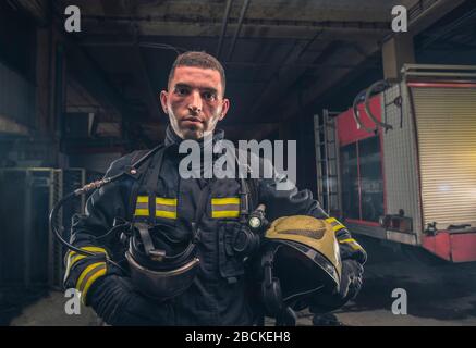 Portrait of a fireman wearing firefighter turnouts holding helmet ready for emergency service. Stock Photo