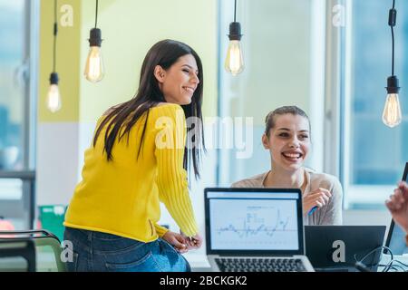Group of professional coworkers ( team ) working on a desk in a modern office on their laptops while talking to each other. Business photo. Stock Photo