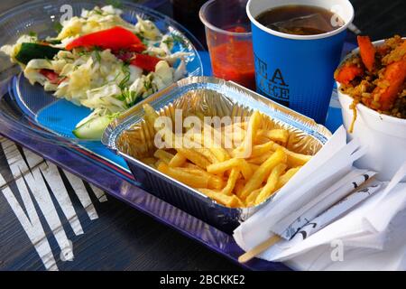Tray with fast food. French fries, salad, sauce, pilaf, glass of tea. Street food and outdoor cooking concept Stock Photo