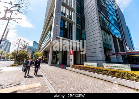 Tokyo, Japan - April 1, 2019: Road street with sign for JP Morgan bank and Mitsubishi electric corporation with Japanese group of young business peopl Stock Photo