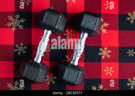 Holiday fitness, pair of 15-pound dumbbells on a holiday background of red and black with gold snowflakes Stock Photo