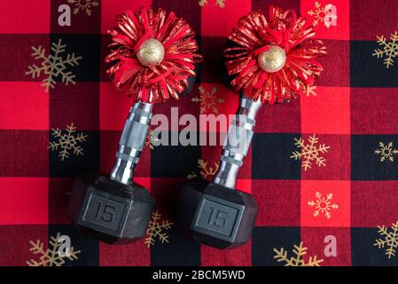 Holiday fitness, pair of 15-pound dumbbells on a holiday background of red and black with gold snowflakes, red and gold bows Stock Photo