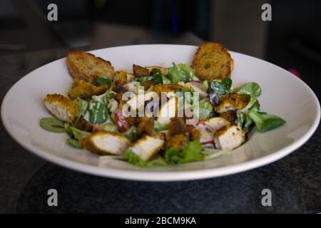 rustic mixed organic salad plate with chicken strips, tomatoes, eggs, bell pepper, lamb's lettuce, balsamic vinegar, croutons and toasted bread, produ Stock Photo