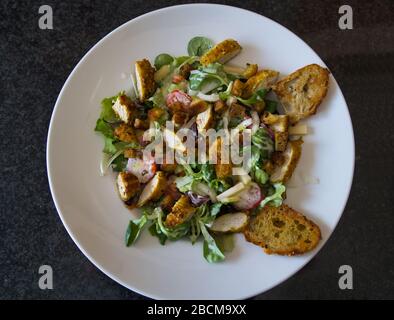 rustic mixed organic salad plate with chicken strips, tomatoes, eggs, bell pepper, lamb's lettuce, balsamic vinegar, croutons and toasted bread, produ Stock Photo