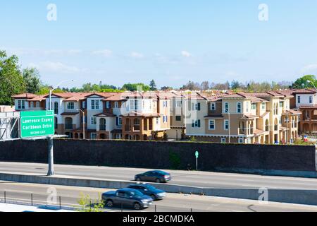 New residential townhomes complex completed next to highway. Concrete noise barrier protects future residents from the motoring sounds of traffic - Su Stock Photo
