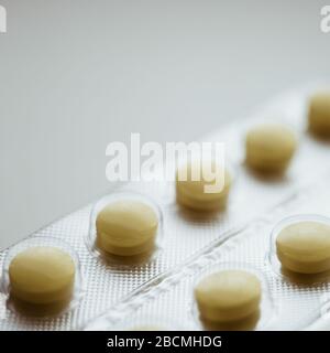 Blister with yellow pills or vitamins closeup, side view. Stock Photo