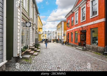 Tourists enjoy sightseeing and shopping on one of the cobblestone streets in the colorful, medieval town of Porvoo, Finland. Stock Photo