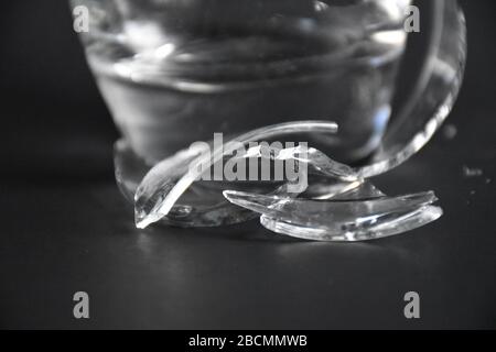 broken glass with pieces and fragments on dark black background, concept of danger Stock Photo