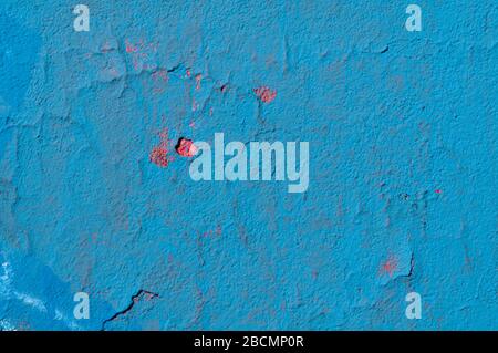 shabby old wall with cracking plaster painted blue over red color Stock Photo