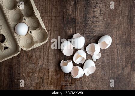 Eight eggshells, empty cardboard egg carton, wood table Stock Photo