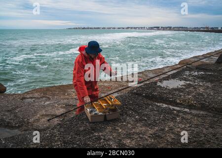 Close-up of a fisherman putting on bait with fishing equipment box. Fishing and sport concept. Stock Photo