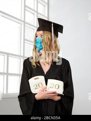 A student is wearing a graduation cape and robe holding toilet paper for a humorous concept of the class of 2020 coronavirus pandemic of the covid-10 Stock Photo