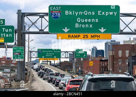 View of Eastbound  Brooklyn-Queens Expressway sign over roadway packed with cars and New York City traffic