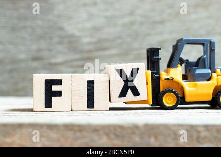 Toy forklift hold letter block x to complete word fix on wood background Stock Photo