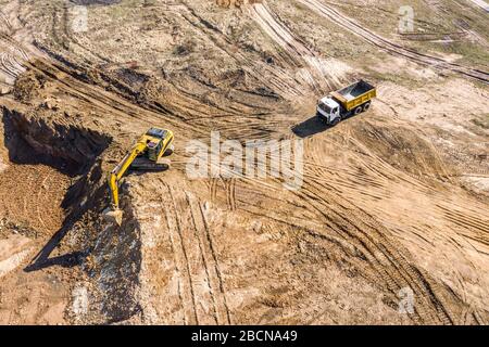 aerial photo of excavator loading sand into the dump truck on construction site Stock Photo