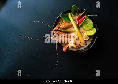 Spicy Tom Yum Goong Sour Soup on black plate table top view, Thai style food Stock Photo