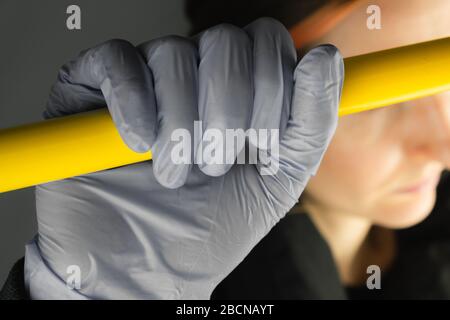 Hand in protective glove holding handlebar in public transport. Concept of personal protection means against virus, gems, covid-19 awareness concept Stock Photo