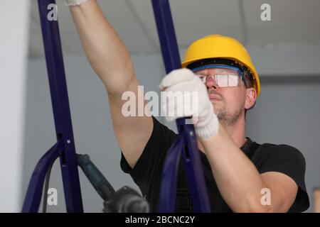 Builder holds metal equipment and looks at ceiling Stock Photo