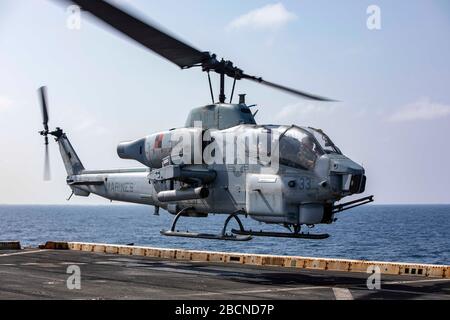 200330-N-GR168-1182 ARABIAN SEA (March 30, 2020) An AH-1W Super Cobra helicopter, attached to the Blue Knights of Marine Medium Tiltrotor Squadron (VMM) 365 (Reinforced), takes off from the flight deck aboard the amphibious transport dock ship USS New York (LPD 21), March 30, 2020. New York, with the Bataan Amphibious Ready Group and with embarked 26th Marine Expeditionary Unit, is deployed to the U.S. 5th Fleet area of operations in support of naval operations to ensure maritime stability and security in the Central Region, connecting the Mediterranean and the Pacific through the Western Indi Stock Photo