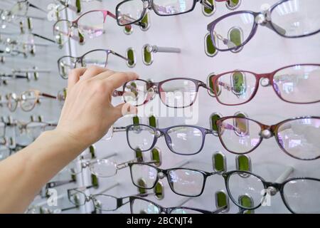 Showcase with glasses in the store, hand choosing glasses