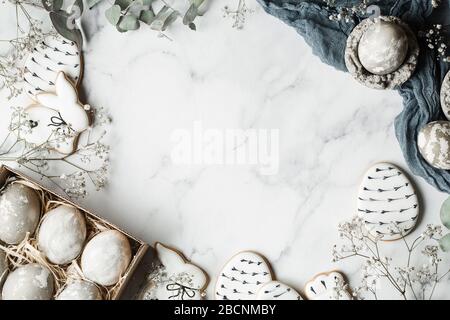 Easter decorations on marble background with copy space. Preparation with grey painted eggs, handmade gingerbread and eucalyptus leaves. Happy holiday Stock Photo