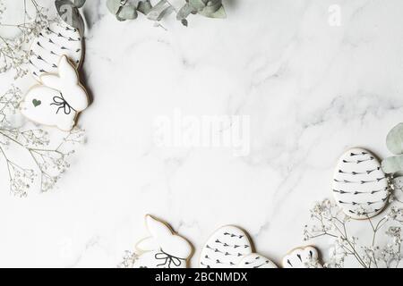 Easter decorations on marble background with copy space. Preparation with grey painted eggs, handmade gingerbread and eucalyptus leaves. Happy holiday Stock Photo