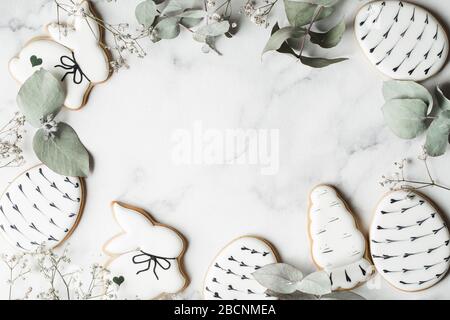 Easter decorations on marble background with copy space. Preparation with grey painted eggs, handmade gingerbread and eucalyptus leaves. Happy holiday Stock Photo