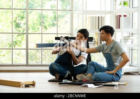 Two carpenters discussed the type of bench being assembled. Handyman installing wooden bench in new house. House renovation service. Morning work atmo Stock Photo
