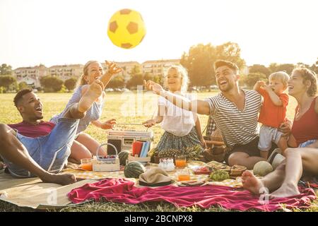 Happy families doing picnic in city park - Young parents having fun with their children in summer time eating, drinking and laughing together - Love a Stock Photo