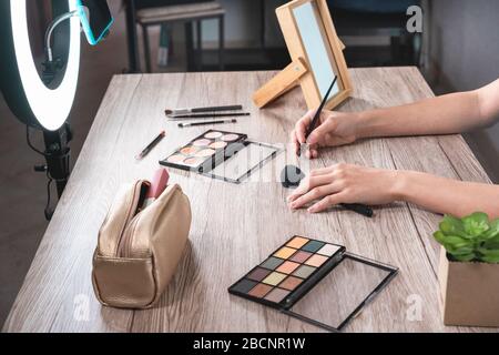 Young influencer woman creating social media videos with smartphone while putting on make up - New digital jobs trends, technology, cosmetics and fash Stock Photo