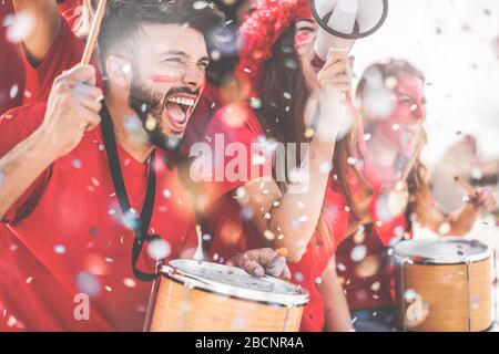 Football supporter fans cheering with confetti watching soccer match event at stadium - Young people group with having excited fun on sport championsh Stock Photo