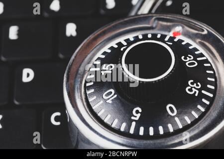 Strong steel coded lock, padlock laying on a black laptop keyboard, macro, closeup IT security policies, passwords codes management, account security Stock Photo