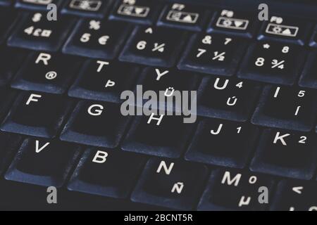 Old black dirty heavily used laptop notebook slightly dusty keyboard with special signs, matte shot, closeup. Vintage second hand pc, flat keyboard Stock Photo