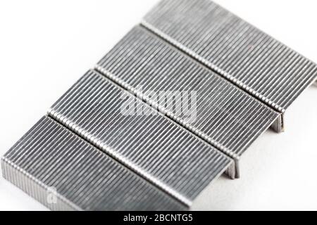 A set of silver metal staples on white, top view, closeup. Office accessories and common workplace items and supplies, office objects concept Stock Photo