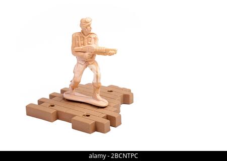 Simple traditional plastic toy soldier standing, holding a machine gun aiming, object isolated on white, cut out People at war, warfare, infantry Stock Photo