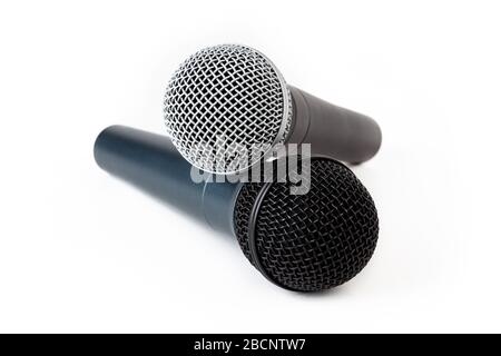 Two microphones laying on top of each other, pair of singing mics together, objects isolated on white background. Singing, podcasting, interview Stock Photo